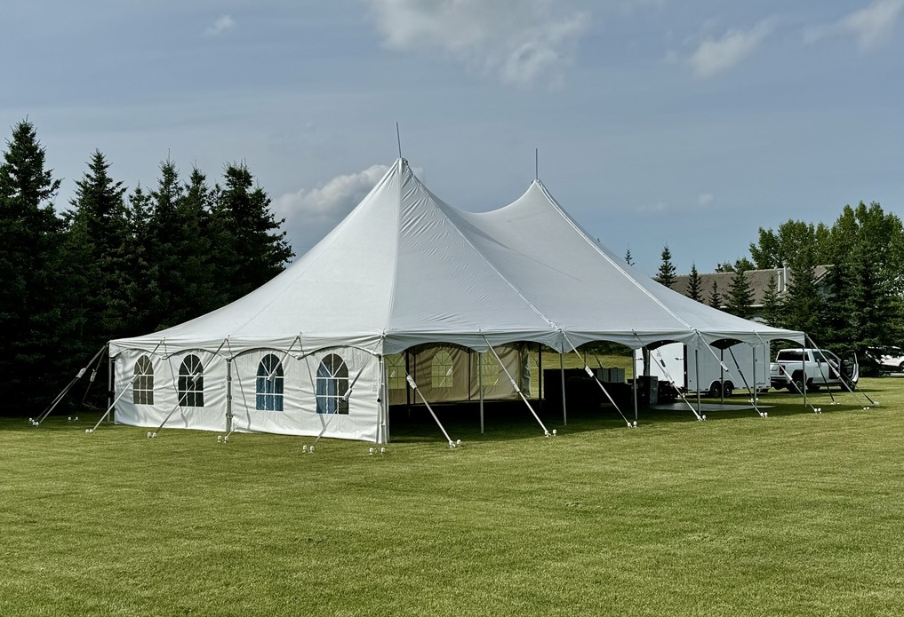 tables and chairs arranged under a pole tent